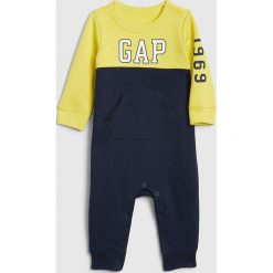 Rampers w kolorze żółto-granatowym. Żółte śpiochy niemowlęce Gap Kids, z nadrukiem. W wyprzedaży za 82,95 zł.