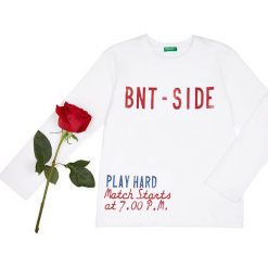 Koszulka w kolorze białym. Białe t-shirty chłopięce Benetton Kids, z nadrukiem, z bawełny, z długim rękawem. W wyprzedaży za 22,95 zł.