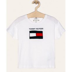 Tommy Hilfiger - T-shirt dziecięcy. Białe bluzki dziewczęce TOMMY HILFIGER, z aplikacjami, z bawełny, z okrągłym kołnierzem, z krótkim rękawem, krótkie, bez kaptura. W wyprzedaży za 129,90 zł.