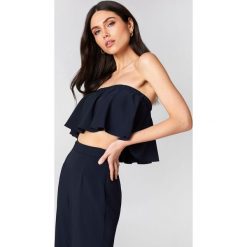 Linn Ahlborg x NA-KD Krótki top z falbaną - Blue. Niebieskie topy damskie marki Linn Ahlborg x NA-KD, bez wzorów, bez kołnierzyka. W wyprzedaży za 50,47 zł.