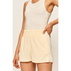 Adidas Originals - Szorty. Żółte spodenki sportowe damskie adidas Originals, z aplikacjami, z poliesteru, sportowe, z podwyższonym stanem. Za 99,90 zł.