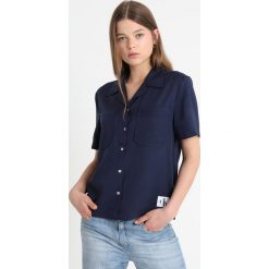 Calvin Klein Jeans POCKET DRAPEY TENCEL SHORT SLEEVE SHIRT Koszula peacoat. Niebieskie bluzki damskie marki Calvin Klein Jeans, l, bez wzorów, z lyocellu, bez kołnierzyka, bez rękawów. Za 399,00 zł.