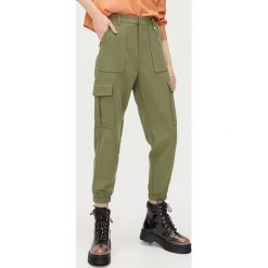 Spodnie z kieszeniami cargo i łańcuchem - Khaki. Brązowe spodnie damskie Cropp. Za 99,99 zł.