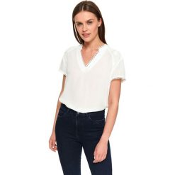 Elegancka bluzka damska. Białe bluzki damskie Top Secret, w koronkowe wzory, z koronki, eleganckie, z dekoltem w serek, z krótkim rękawem. W wyprzedaży za 44,99 zł.