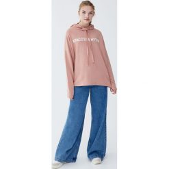 Bluza z kapturem i napisem po rosyjsku. Różowe bluzy damskie Pull&Bear, z napisami, bez rękawów, z kapturem. Za 59,90 zł.