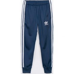 Adidas Originals - Spodnie dziecięce 128-164 cm. Niebieskie spodnie chłopięce marki adidas Originals, bez wzorów, z poliesteru, sportowe. W wyprzedaży za 129,90 zł.
