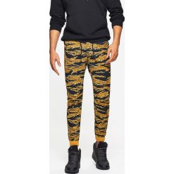 Dresowe joggery camo - Brązowy. Pomarańczowe bez kategorii marki Cropp, z dresówki. W wyprzedaży za 39,99 zł.