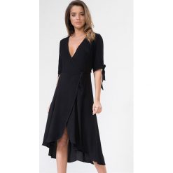 Sukienka w kolorze czarnym. Czarne sukienki damskie Urban Touch, bez wzorów, bez kołnierzyka, bez rękawów, midi, kopertowe. W wyprzedaży za 119,95 zł.