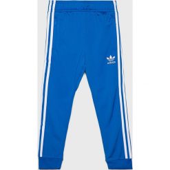 Adidas Originals - Spodnie dziecięce. Niebieskie spodnie chłopięce adidas Originals, bez wzorów, z poliesteru. W wyprzedaży za 119,90 zł.
