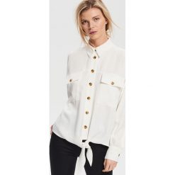Koszula oversize z wiązaniem - Kremowy. Białe koszule damskie Reserved, bez wzorów, bez kołnierzyka, bez rękawów. Za 139,99 zł.