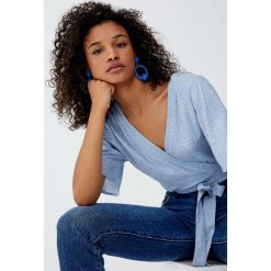Top z kopertowym dekoltem i drobnym nadrukiem. Szare topy damskie Pull&Bear, z nadrukiem, bez kołnierzyka, z krótkim rękawem. Za 79,90 zł.