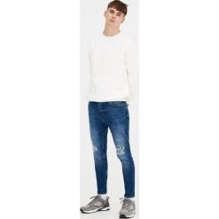 Postrzępione jeansy carrot fit. Niebieskie jeansy męskie marki Pull&Bear, m, bez wzorów. Za 139,00 zł.