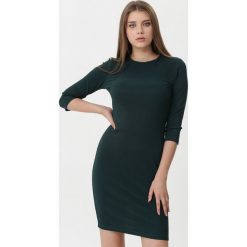 Ciemnozielona Sukienka Yvette. Sukienki damskie Born2be, na imprezę, na jesień, s, bez wzorów, z dzianiny, z okrągłym kołnierzem, bez rękawów, midi, dopasowane. Za 69,99 zł.