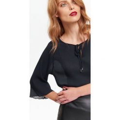 Plisowana bluzka damska z wiązaniem i szerokim rękawem. Czarne bluzki damskie Top Secret, bez wzorów, z tkaniny, eleganckie, bez kołnierzyka, bez rękawów. W wyprzedaży za 49,99 zł.