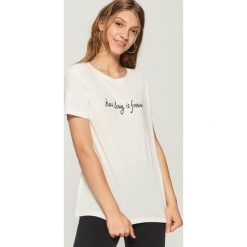 T-shirt z napisem - Kremowy. Białe t-shirty damskie marki Sinsay, l, z napisami. W wyprzedaży za 14,99 zł.