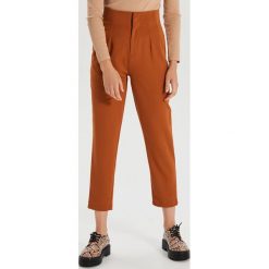 Materiałowe spodnie high waist - Brązowy. Pomarańczowe spodnie damskie Cropp, z tkaniny, z podwyższonym stanem. W wyprzedaży za 29,99 zł.
