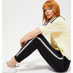 Spodnie dresowe z lampasami. Czarne spodnie damskie Moodo, xs, bez wzorów, z bawełny. Za 59,99 zł.