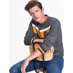 BLUZA NIEROZPINANA MĘSKA Z KONTRASTOWĄ APLIKACJĄ. Szare bluzy męskie Top Secret, xl, w paski, z dzianiny, z kontrastowym kołnierzykiem, bez rękawów, bez kaptura. W wyprzedaży za 49,99 zł.