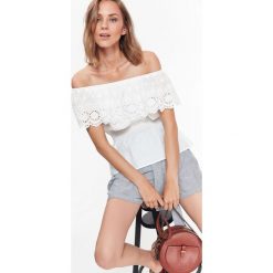 Bluzka z haftowaną falbaną. Białe bluzki damskie Top Secret, w koronkowe wzory, z tkaniny, eleganckie, z falbankami, bez rękawów. W wyprzedaży za 39,99 zł.