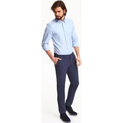 Koszula męska o kroju regularnym ze strukturalnej tkaniny i kołnierzem typu button down. Niebieskie koszule męskie Top Secret, m, bez wzorów, z bawełny, eleganckie, z klasycznym kołnierzykiem, bez rękawów. Za 99,99 zł.