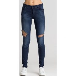 Granatowe jeansy z ozdobną siatką Curve X. Niebieskie jeansy damskie Guess. Za 299,50 zł.