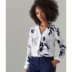 Elegancka bluzka w kwiaty - Biały. Białe bluzki damskie marki Mohito, w kwiaty, eleganckie, bez kołnierzyka, bez rękawów. Za 99,99 zł.