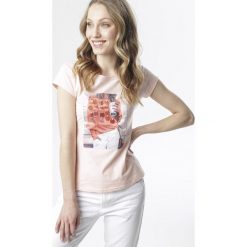 Jasnoróżowy T-shirt Meridina. Różowe bluzki damskie Born2be, s, bez wzorów, bez kołnierzyka, bez rękawów. W wyprzedaży za 39,99 zł.