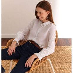Bluzka długi rękaw o luźnym kroju, reglan. Białe bluzki damskie Top Secret, bez wzorów, z tkaniny, eleganckie, z falbankami, z długim rękawem. W wyprzedaży za 59,99 zł.