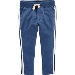 Spodnie dresowe w kolorze niebieskim. Niebieskie spodnie niemowlęce OshKosh, w paski, z dresówki. W wyprzedaży za 37,95 zł.