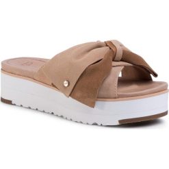 Klapki UGG - W Joanie 1107885 Bnz. Brązowe klapki damskie Ugg, z aplikacjami, ze skóry, bez obcasa, na koturnie. Za 599,00 zł.