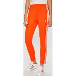 Adidas Originals - Spodnie. Pomarańczowe spodnie damskie adidas Originals, bez wzorów, z elastanu, casualowe. Za 199,90 zł.