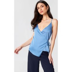 Linn Ahlborg x NA-KD Kopertowy top z satyny - Blue. Niebieskie topy damskie marki Linn Ahlborg x NA-KD, bez wzorów, z satyny, bez kołnierzyka. W wyprzedaży za 45,20 zł.