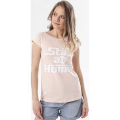 Jasnoróżowy T-shirt Noelori. Różowe bluzki damskie Born2be, s, bez wzorów, bez kołnierzyka, bez rękawów. W wyprzedaży za 49,99 zł.