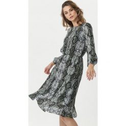 Ciemnozielona Sukienka Blackett. Zielone sukienki damskie Born2be, z nadrukiem, ze skóry, eleganckie, z okrągłym kołnierzem, z długim rękawem, długie, maxi, rozkloszowane. Za 139,99 zł.