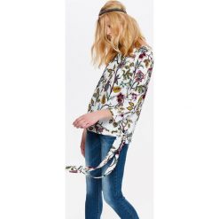 DAMSKA BLUZKA W KWIATY Z WIĄZANIEM NA BOKU. Białe bluzki damskie Top Secret, w kwiaty, z tkaniny, eleganckie, bez kołnierzyka, bez rękawów. W wyprzedaży za 39,99 zł.