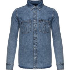 Koszula Calvin Klein Jeans Utility Omega J30J311937. Niebieskie koszule męskie Calvin Klein Jeans, m, bez wzorów, z bawełny, casualowe, bez kołnierzyka, bez rękawów. W wyprzedaży za 209,00 zł.