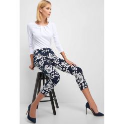 Cygaretki w kwiaty. Niebieskie spodnie damskie Orsay, z haftami, z elastanu, eleganckie. Za 79,99 zł.