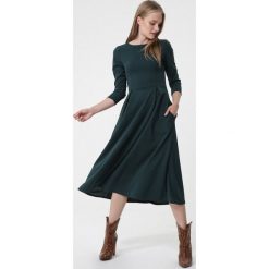 Ciemnozielona Sukienka Portobello. Zielone sukienki damskie Born2be, na co dzień, s, bez wzorów, eleganckie, z okrągłym kołnierzem, bez rękawów, midi, rozkloszowane. Za 99,99 zł.