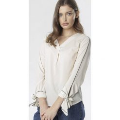 Kremowa Bluzka Ocerah. Brązowe bluzki damskie Born2be, do pracy, bez wzorów, eleganckie, bez kołnierzyka, z długim rękawem. Za 59,99 zł.