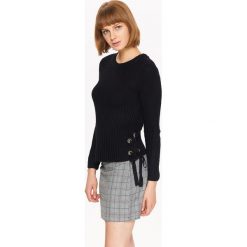 Sweter damski z ozdobnymi wiązaniami po bokach. Czarne swetry damskie TROLL, na zimę, xs, bez wzorów, z dzianiny, eleganckie, z długim rękawem, długie, bez kaptura. W wyprzedaży za 29,99 zł.