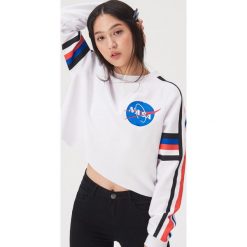 Krótka bluza z motywem NASA - Biały. Białe bluzy damskie Sinsay, s, bez wzorów, z krótkim rękawem, krótkie, bez kaptura. Za 49,99 zł.