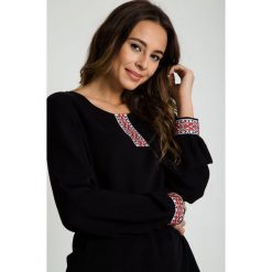 Czarna bluzka z ozdobną taśmą przy dekolcie RABARBAR. Czarne bluzki damskie RABARBAR, m, bez wzorów, biznesowe, bez kołnierzyka, bez rękawów. W wyprzedaży za 139,00 zł.