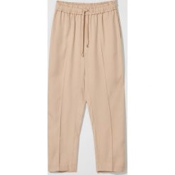 Spodnie jogger fit z wysokim stanem - Beżowy. Brązowe spodnie damskie Mohito, bez wzorów, z podwyższonym stanem. W wyprzedaży za 79,99 zł.