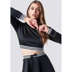 Pamela x NA-KD Krótka bluza sportowa - Black. Czarne bluzy damskie marki Pamela x NA-KD, w paski, z krótkim rękawem, długie, bez kaptura. W wyprzedaży za 80,97 zł.