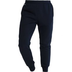 Lacoste Sport Spodnie treningowe navy blue. Niebieskie spodnie męskie marki Lacoste Sport, m, bez wzorów, z bawełny, sportowe, długie. Za 369,00 zł.