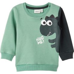 Bluza "Nikus" w kolorze zielonym. Zielone bluzy niemowlęce name it boys, z nadrukiem, z bawełny, bez rękawów, bez kaptura. W wyprzedaży za 37,95 zł.