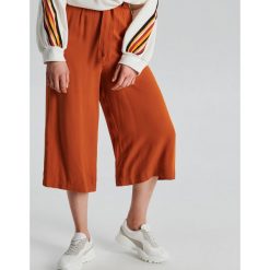 Lekkie spodnie culotte z wiskozy - Pomarańczowy. Pomarańczowe spodnie damskie Cropp, z wiskozy. W wyprzedaży za 29,99 zł.