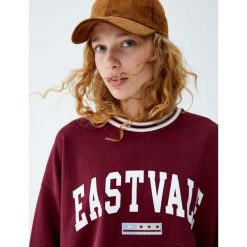 Bluza z napisem w stylu college. Czerwone bluzy damskie Pull&Bear, z napisami, bez rękawów, bez kaptura. Za 69,90 zł.