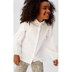 Mango Kids - Koszula dziecięca Nil 122-164 cm. Białe bluzki dziewczęce Mango Kids, bez wzorów, z bawełny, bez kołnierzyka, z długim rękawem, długie, bez kaptura. Za 89,90 zł.