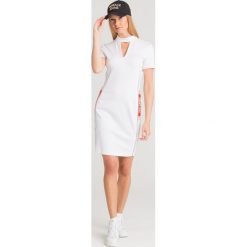 SUKIENKA Versace Jeans. Białe sukienki damskie Versace Jeans, na imprezę, bez wzorów, z elastanu, z włoskim kołnierzykiem, bez rękawów, mini, dopasowane. Za 601,30 zł.